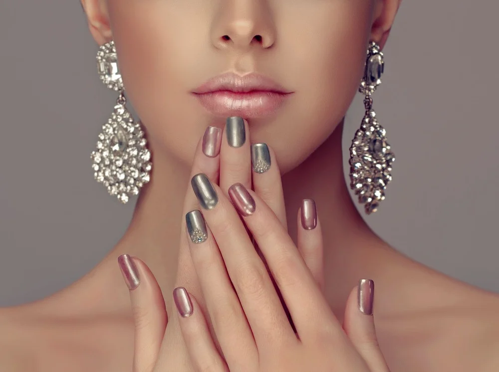 Schönes Model mit pink-grau-silberner Metallic-Maniküre auf den Nägeln.